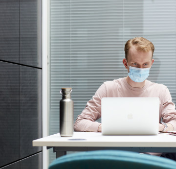 male student on a laptop in a mask