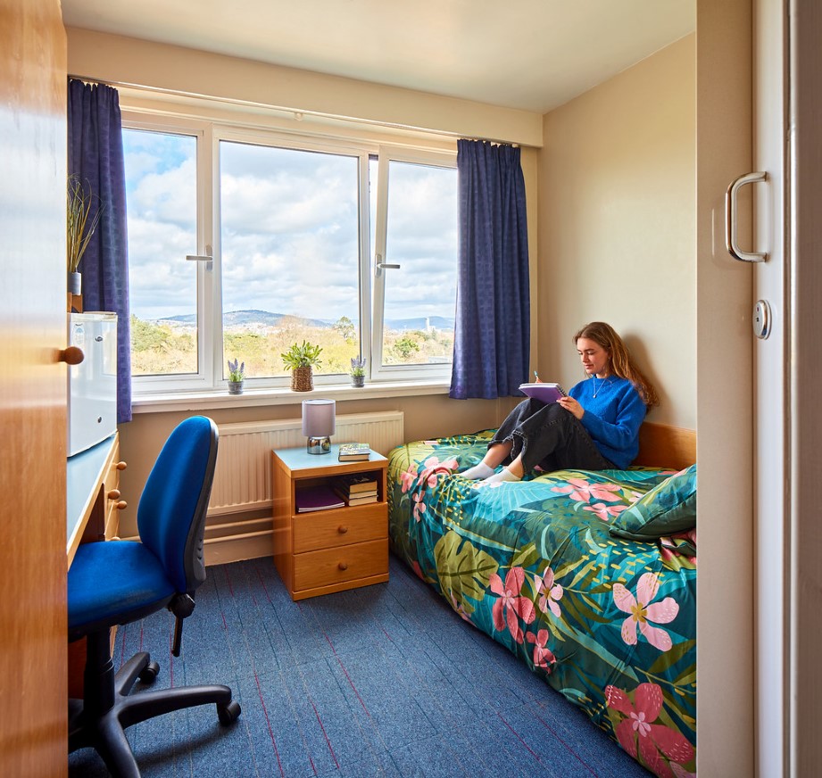 Student sitting on a bed in an Ensuite room.