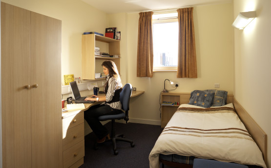 Student sitting at desk in bedroom.