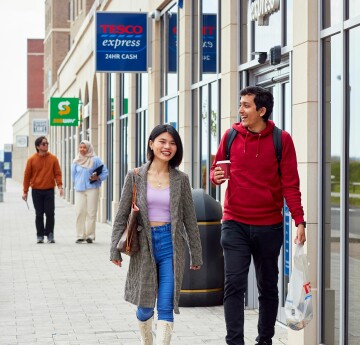 Two students walking past Tesco Express and Subway