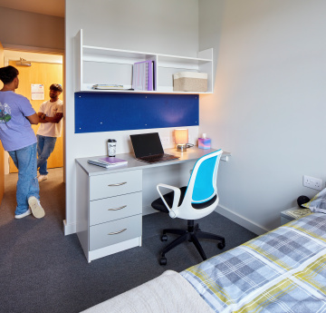 An image of two students talking to each other near a door in student accommodation on Bay Campus.