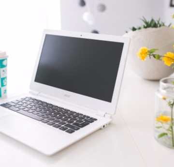 Laptop on a desk with flowers in a bright image