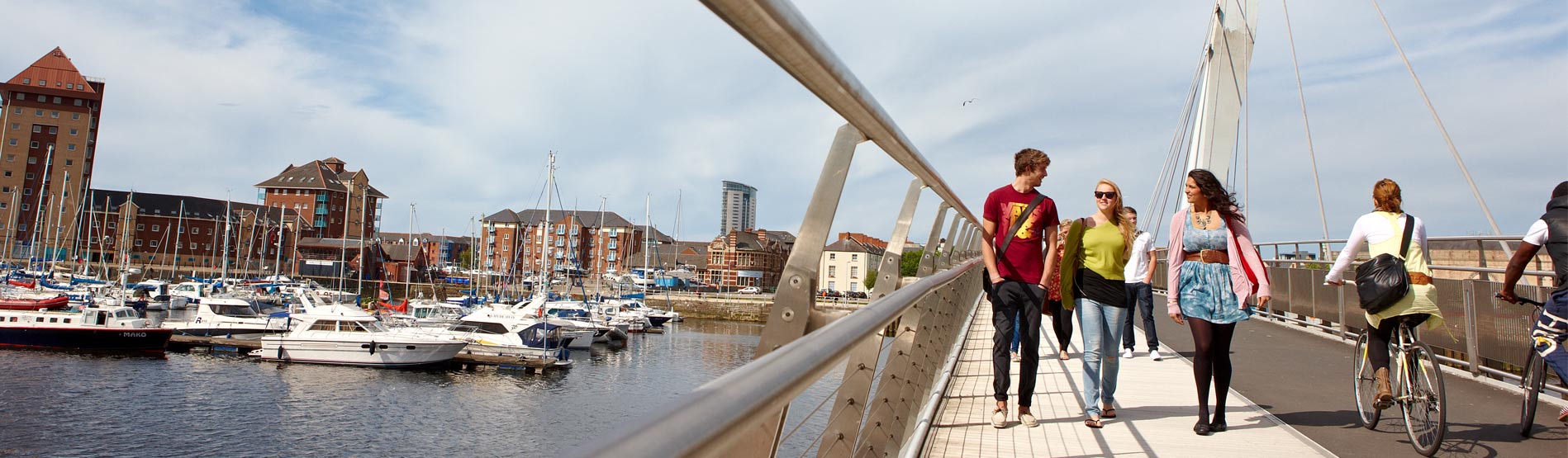People walking over the bridge in SA1, Swansea with the Marina in the Background