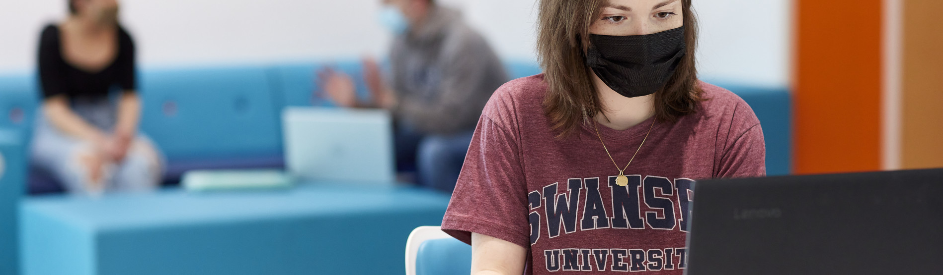 a female student on a laptop wearing a mask 