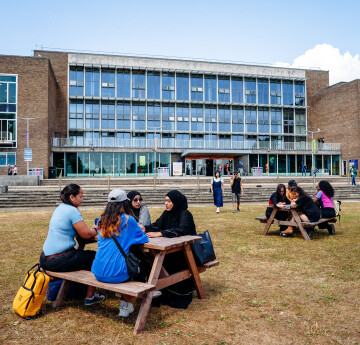  Photograph of students sitting at a bench on the lawn outside Fulton House, Singleton Park Campus