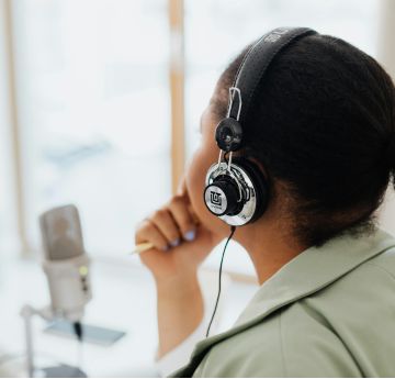 Person sat in front of microphone with headphones on