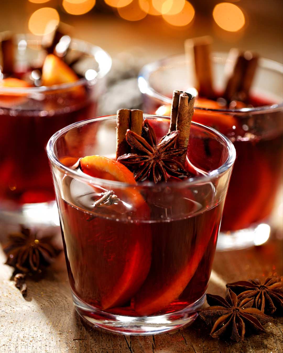 Warm mulled wine in a glass with an orange zest and cinnamon sticks