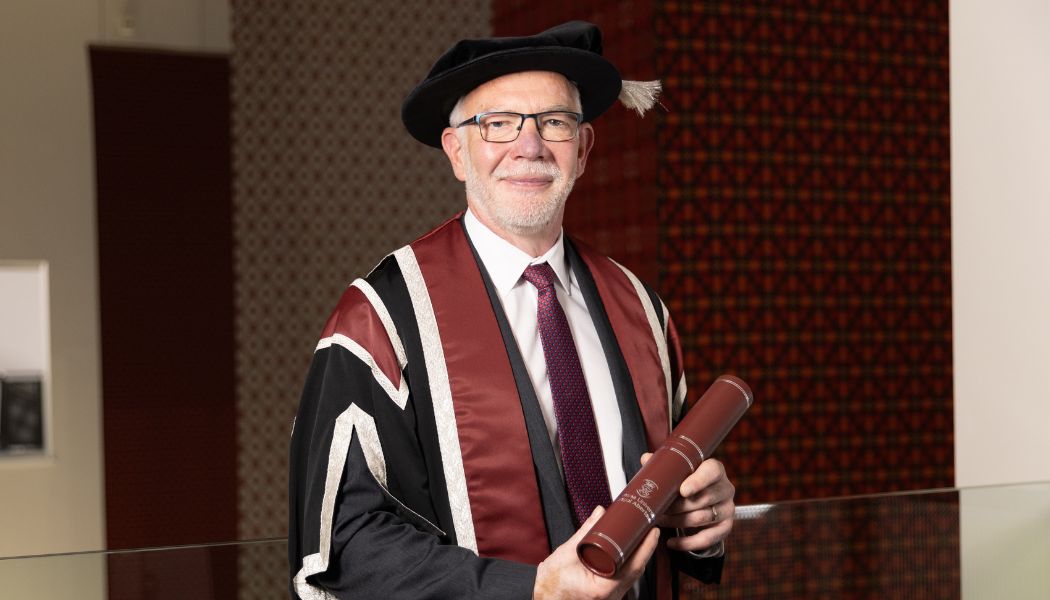 Man wearing cap & gown smiling for the camera