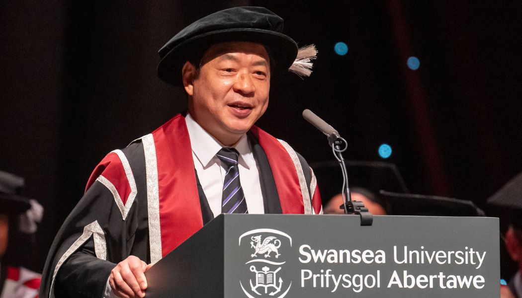Man wearing cap & gown smiling at the camera