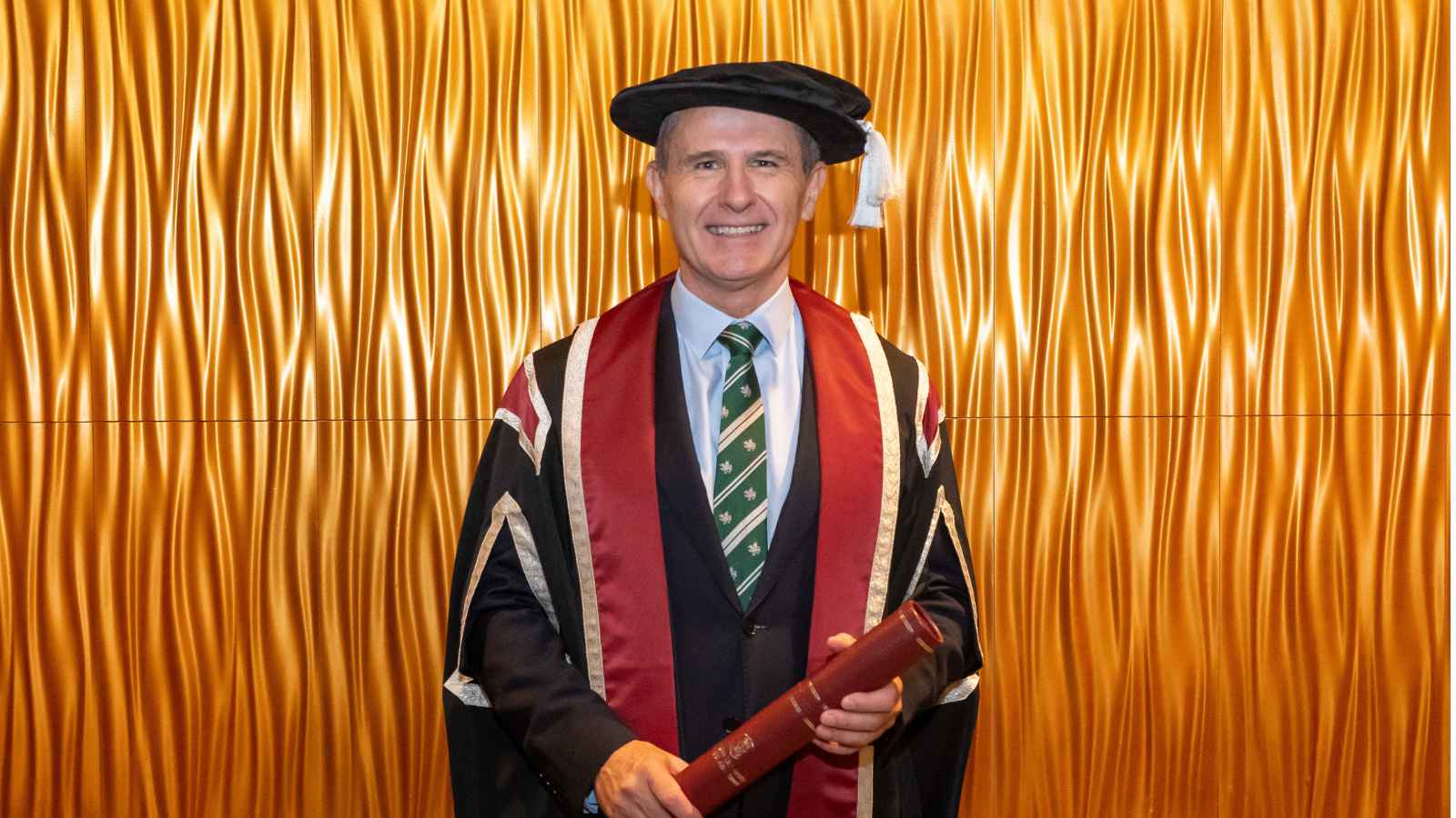 Man wearing cap & gown smiling at the camera