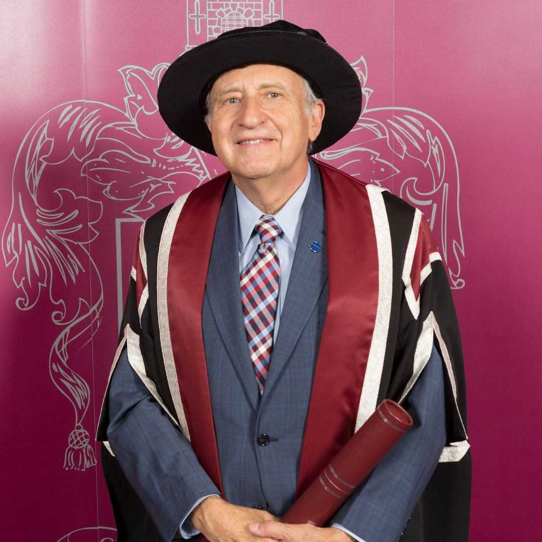 Man wearing cap and gown smiling at the camera