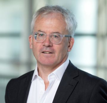 Man in a suit and tie standing in front of a glass office