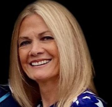 Photo of a lady with blonde hair smiling directly at the camera. 