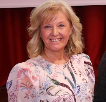Photo of a lady in a colourful dress smiling at the camera