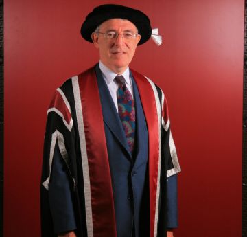 Man wearing cap & gown posing for the camera