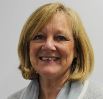 Lady with blonde hair smiling against a white backdrop