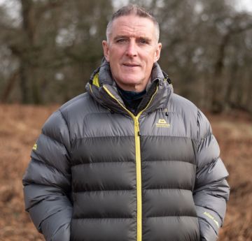 Man wearing a warm coat smiling at the camera outdoors