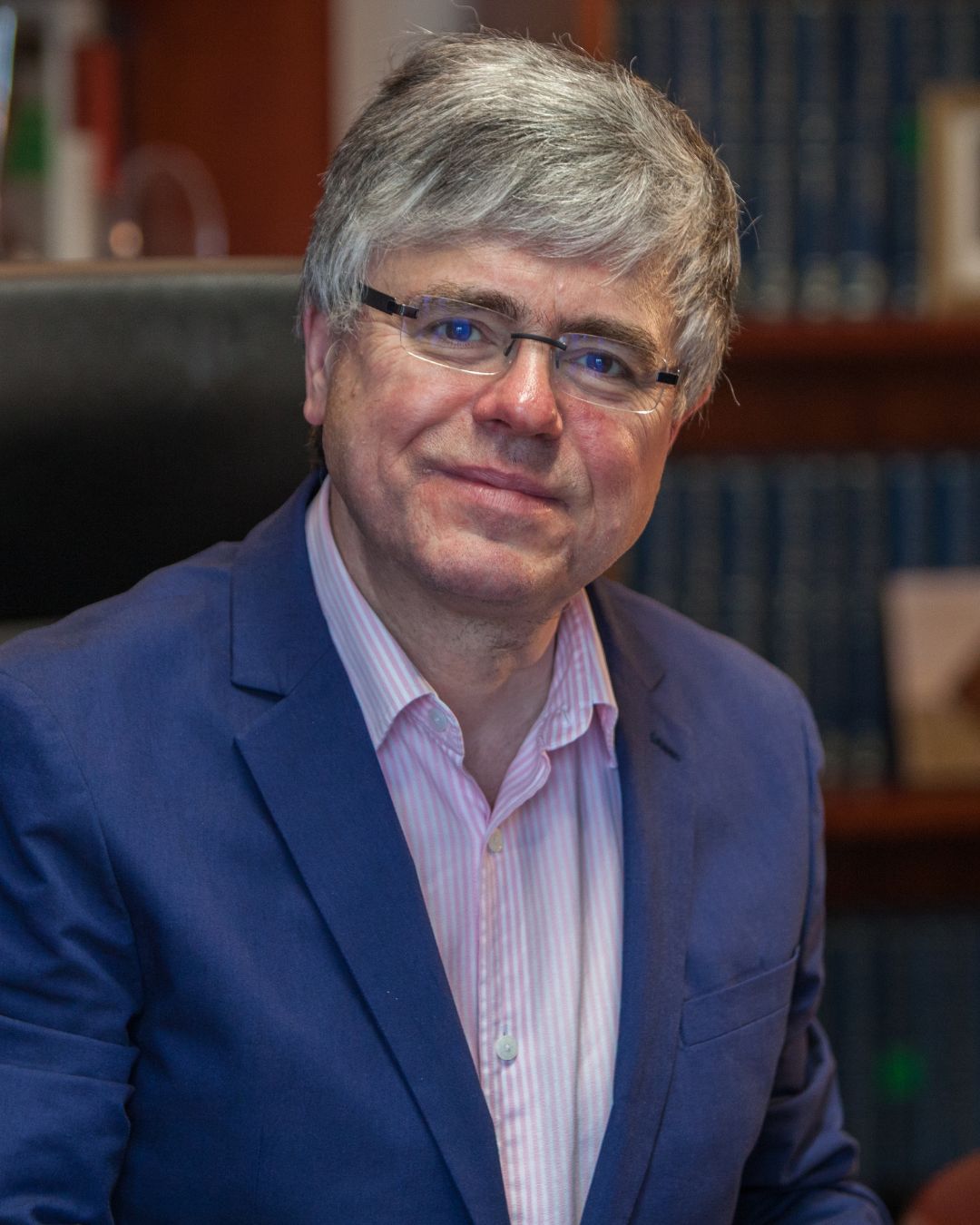 Gentleman in suit sitting at the desk smiling at the camera