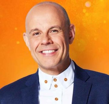 Man smiling at the camera with an orange background