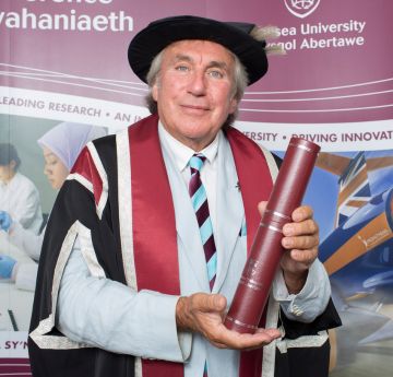 Man wearing cap and gown holding a scroll