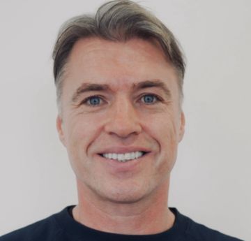 Man with brown hair looking at the camera smiling