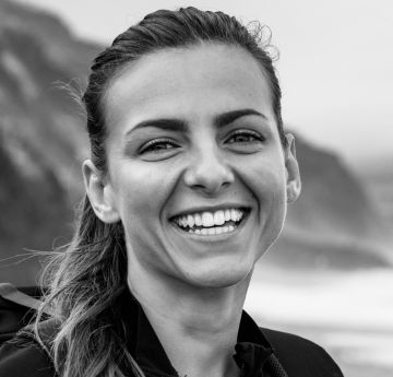 Lady standing by the water smiling at the camera