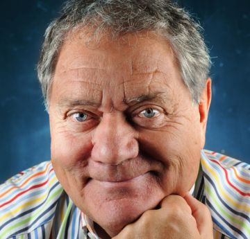 Man in a coloured striped shirt smiling at the camera