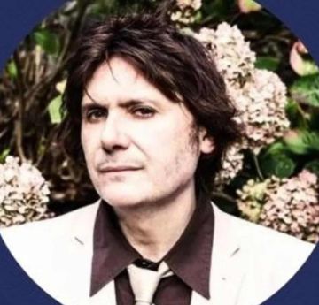 Profile picture of a man looking at the camera with flowers in the background