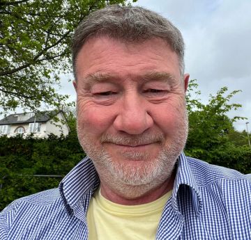 Man in a shirt outside smiling at the camera