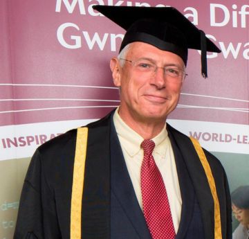 Man in cap and gown smiling at the camera