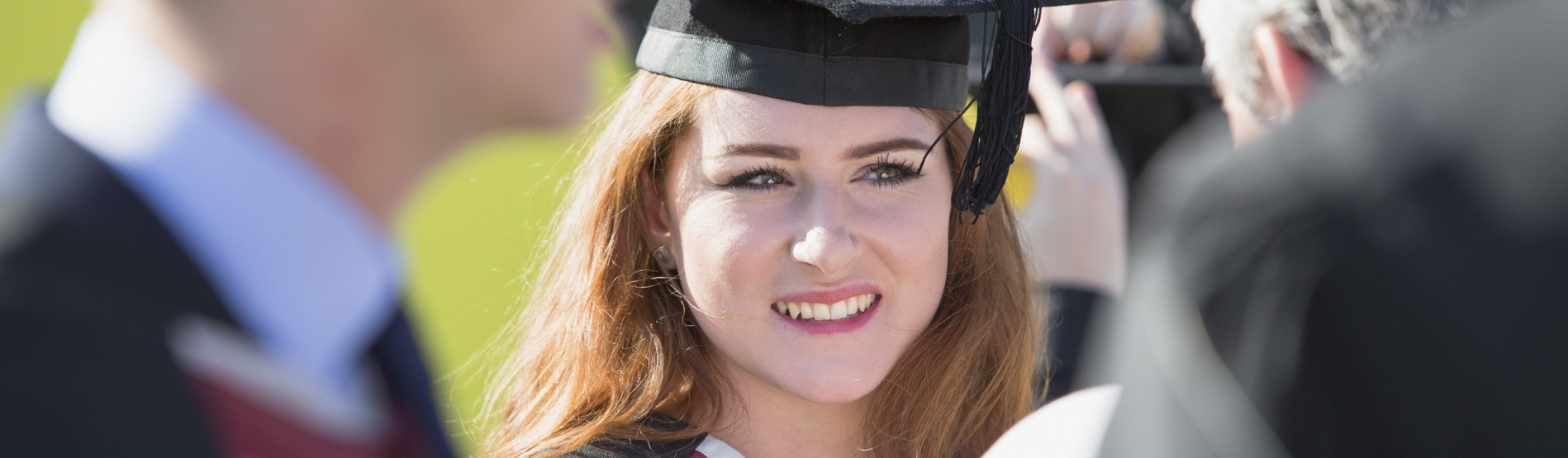 Young female smiling at Graduation wearing cap and gown 