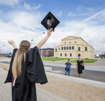 girl at grad with arms in air 