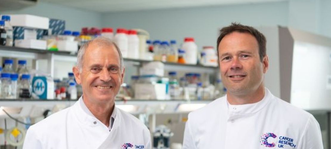 Professor Paul Dyson and collaborator Dr Lee Parry, of Cardiff University. They stand in the lab, dressed in their Cancer Research UK lab coats. 