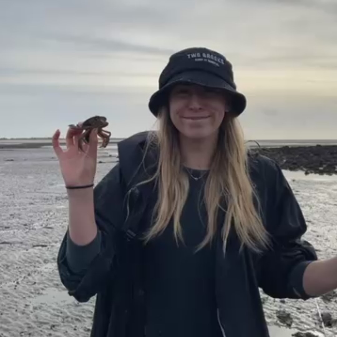 Amelia holding a crab on the beach.