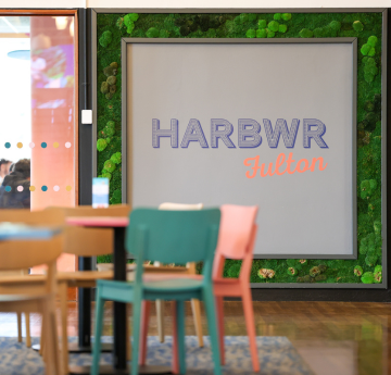 Chairs around a table with Harbwr Fulton sign on the wall behind