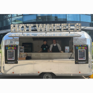 a silver food van with two servers smiling