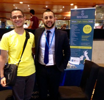 Ahmed Ibrahim at a University Fair in Egypt, stood side by side with a Student Recruitment Officer from Swansea University next to a pull up banner reading 