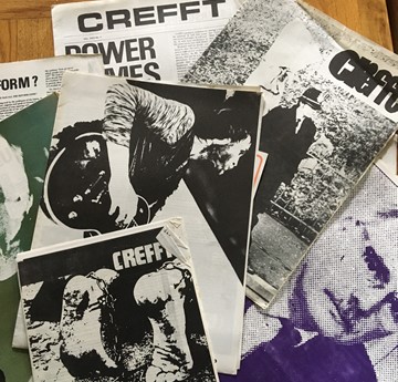 A series of Crefft newspaper front pages from the 1970s laid out on a table