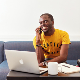 An image of a student sitting at a laptop making a phone call.