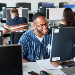 An image of a student working at a computer in a PC lab. 