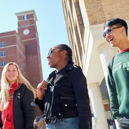 An image of three students walking past the Clock Tower on Bay Campus.