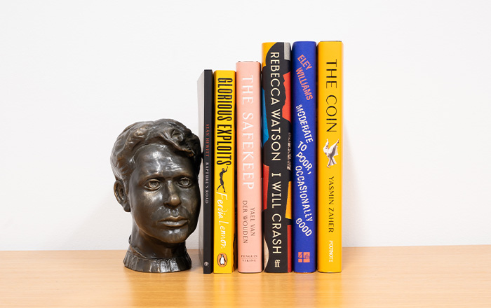 Bookshelf image of the 6 book spines accompanied by bronze bust of Dylan Thomas