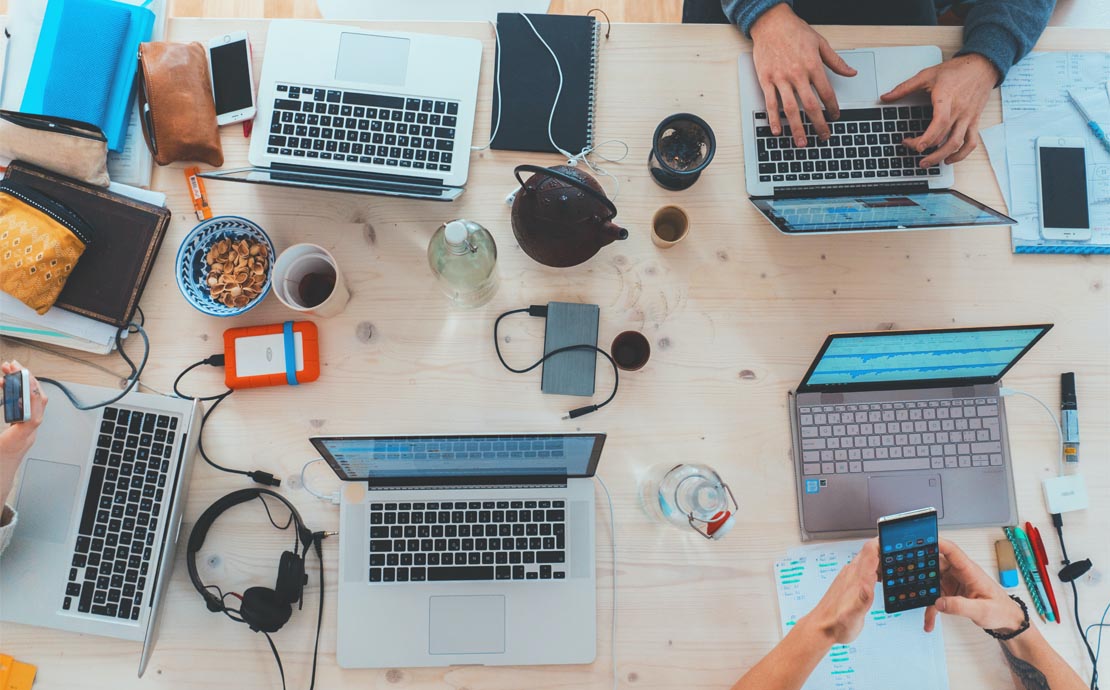 An image of the desk full of people typing on their laptops 