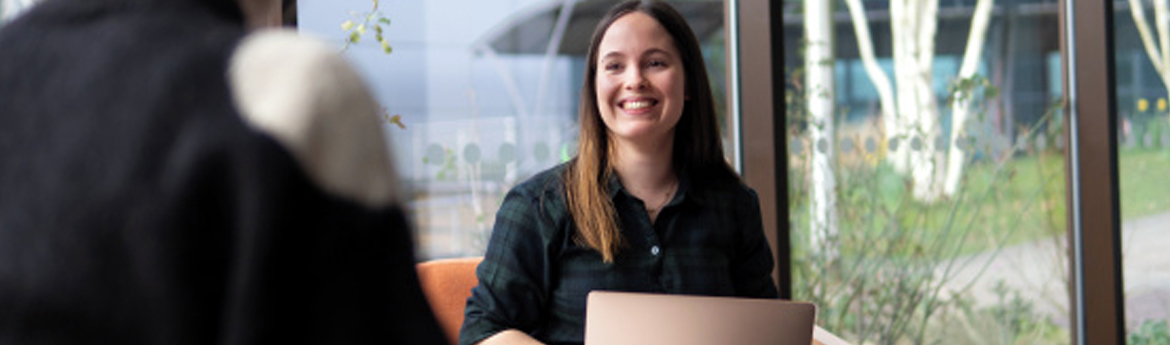 Myfyriwr ar liniadur yn siarad â rhywun