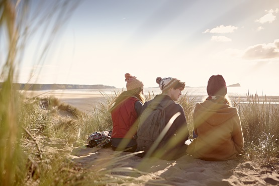 Three students sat on the Swansea beach