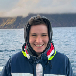 Headshot of Rachel with the sea behind her.
