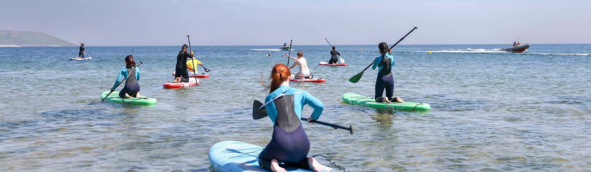 A group of students paddleboarding at a Gower beach