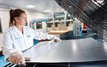 Woman working with a sheet of steel in a lab