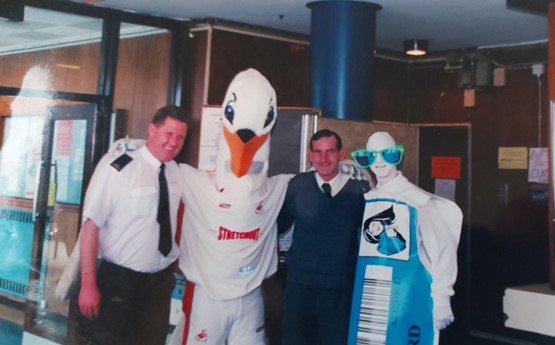 Geraint and a colleague pose with Cyril, the Swans FC mascot and another mascot.