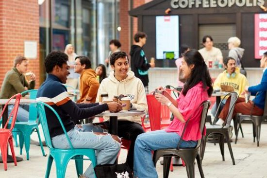 Myfyrwyr yn chwarae ac yn sgwrsio ar y traeth